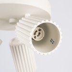 Beżowa lampa sufitowa Karbon z trzema miejscami na żarówki GU10. Ujęcie z bliska, pokazujące detale kloszy z rowkowaną teksturą. Widoczny gniazdo żarówki z oznaczeniem maksymalnej mocy. Proste tło, podkreślające design produktu.