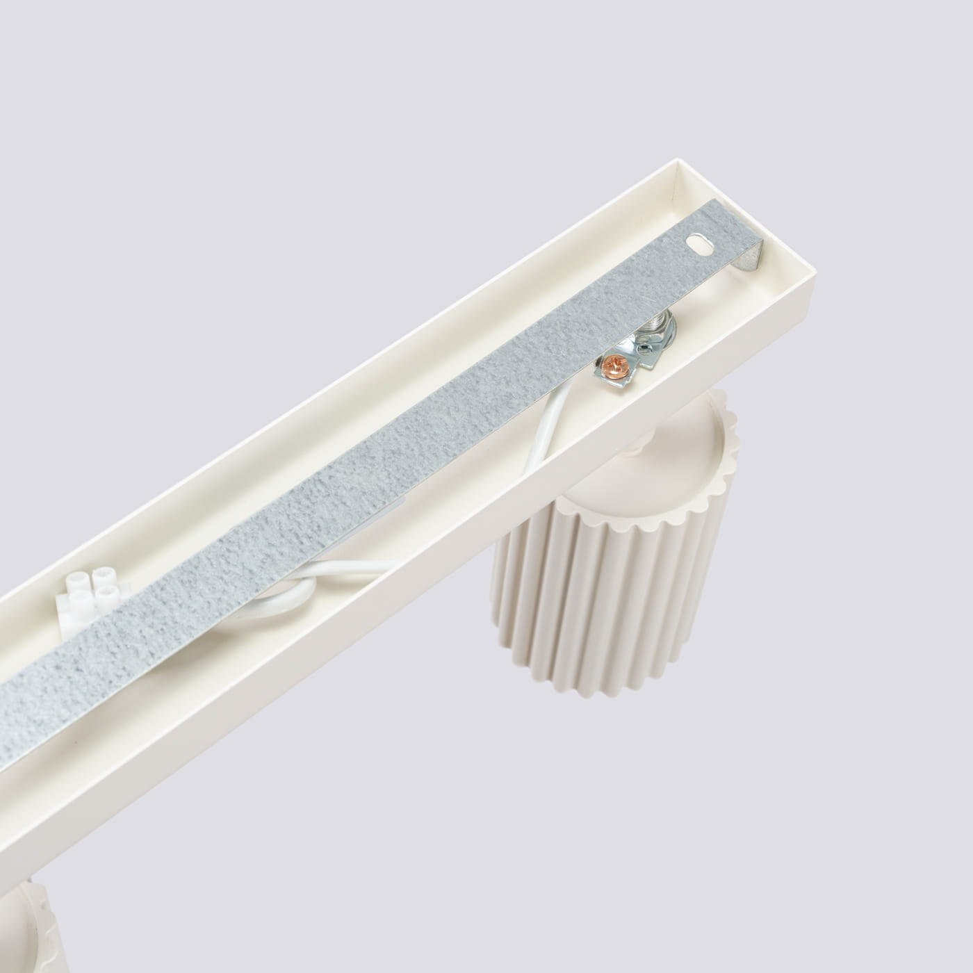 Beżowa lampa sufitowa Karbon L z czterema miejscami na żarówki GU10. Widoczne elementy montażowe, metalowy pasek z przewodami oraz okrągłe, teksturowane detale. Produkt w ułożeniu poziomym, z bliska na część mocującą.