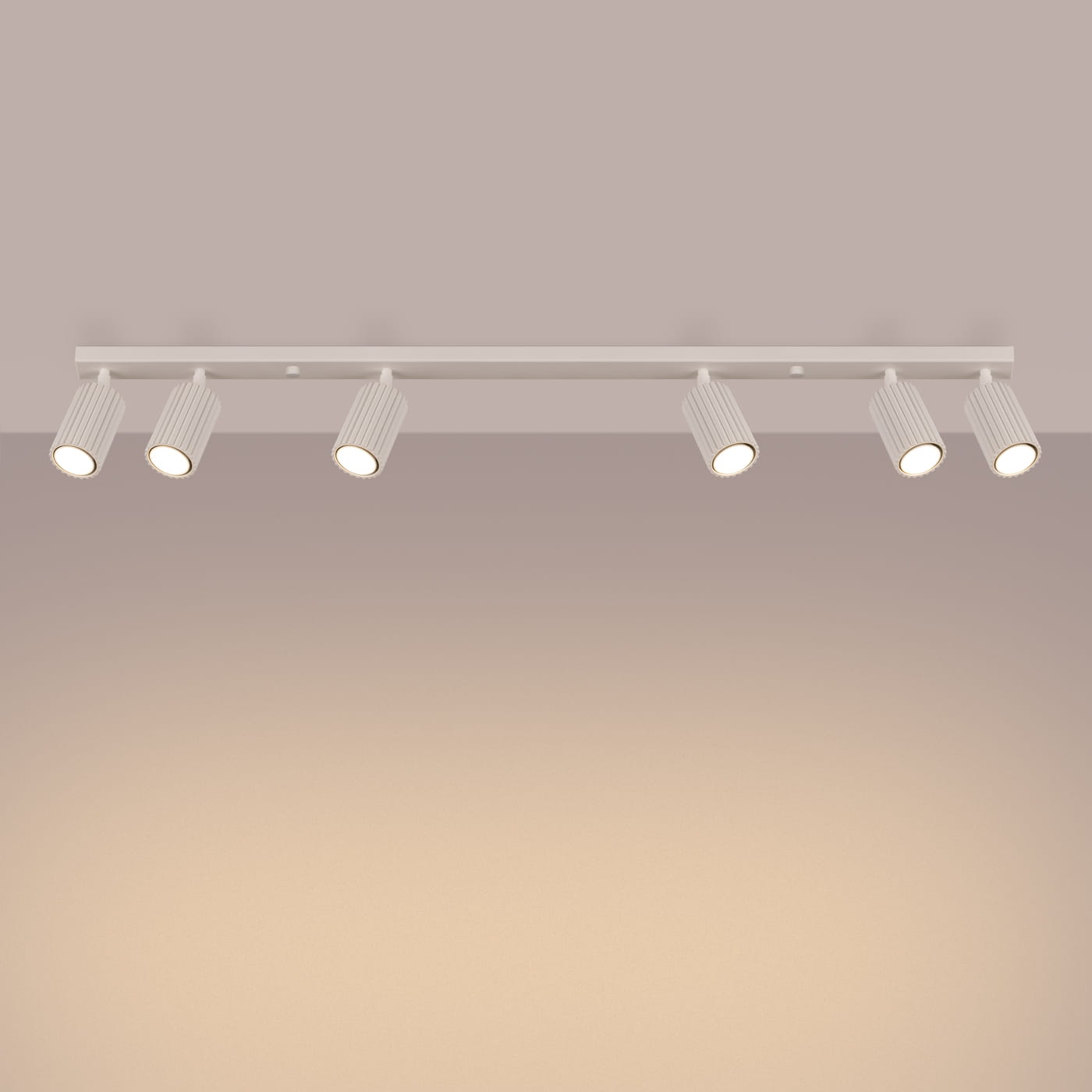 Beżowa lampa sufitowa Karbon z sześcioma reflektorami GU10, umieszczona na prostokątnej, płaskiej podstawie. Reflektory mają cylindryczny kształt z wyżłobieniami, skierowane w różne strony. Produkt zamontowany na ścianie w neutralnym otoczeniu.