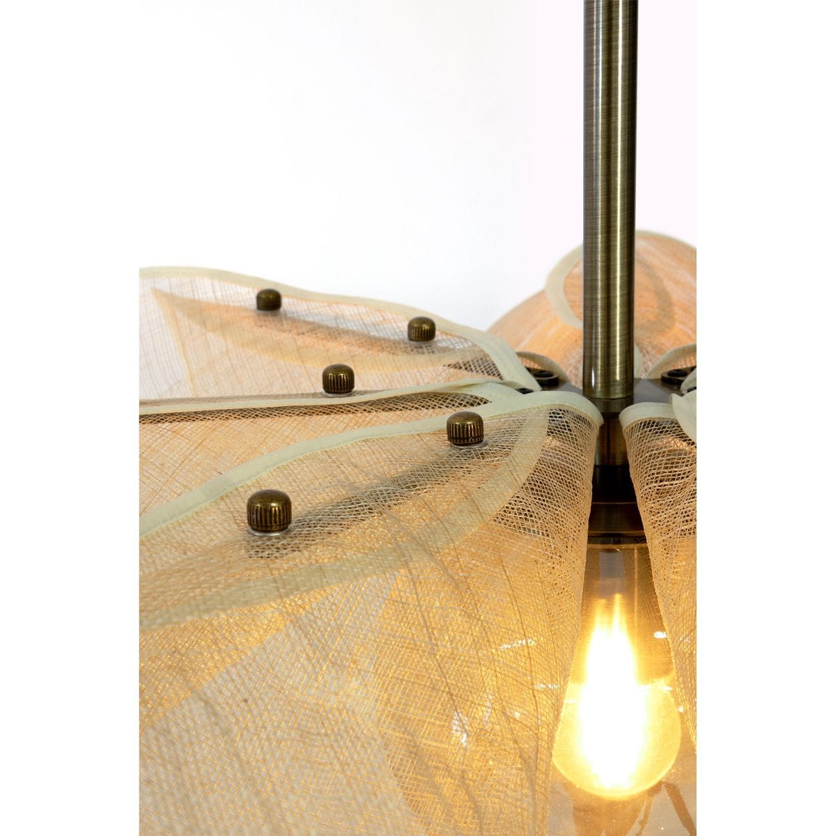 Lampa wisząca Styrka z antycznym mosiądzu, z kloszem w odcieniu bursztynowym i beżowym. Klosz z delikatnej siatki z ozdobnymi guzikami, zawieszony na stalowym stelażu, z widoczną żarówką E27. Ujęcie z góry, podkreślające detale i fakturę materiału.
