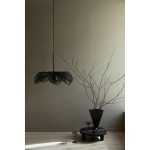 Lampa wisząca Styrka w kolorze czarnym z dymnym kloszem, zawieszona na cienkim przewodzie. Kształt klosza przypomina kwiat, a lampa jest umieszczona w minimalistycznym otoczeniu z drewnianą podłogą i dekoracyjnymi elementami.