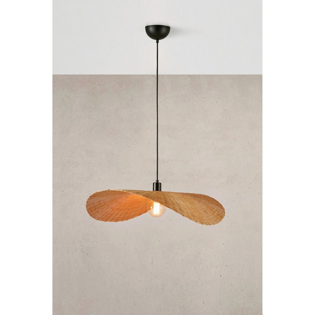 Lampa wisząca Rayo z oprawą w kolorze czarnym i kloszem w naturalnym odcieniu, zawieszona na cienkim przewodzie. Kształt klosza przypomina dwa skrzydła, odsłaniając żarówkę E27. Tło w jasnym odcieniu betonu.