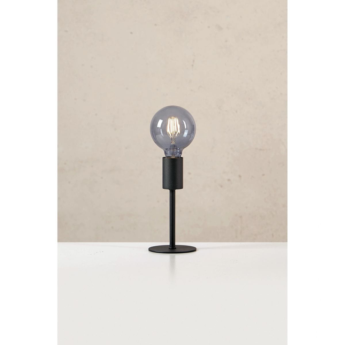 Lampa stołowa Cielo z jedną oprawą E27, w kolorze piaskowym i czarnym. Prosta podstawa z metalowym słupkiem, na której umieszczona jest przezroczysta kula z żarówką. Ujęcie frontalne, na białym tle.