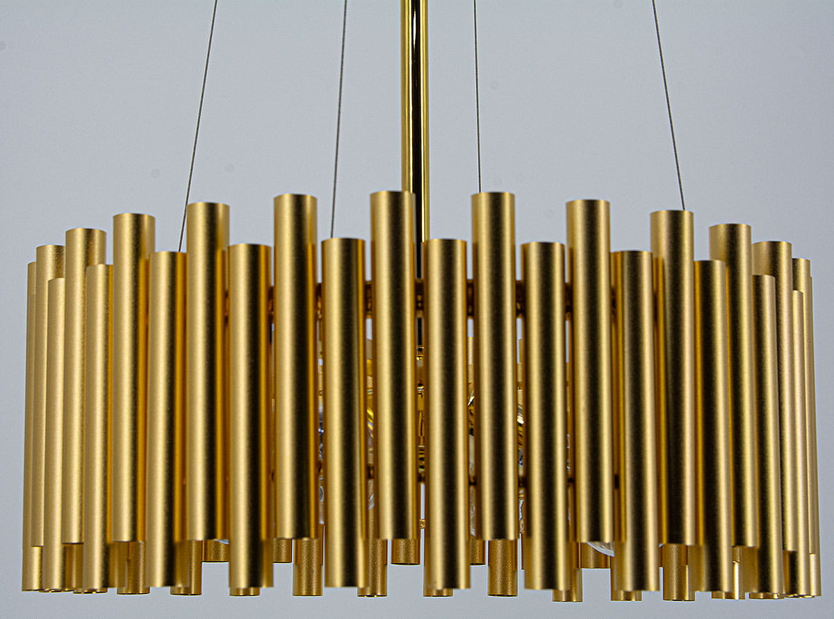 Lampa wisząca Narni 4xE27 w kolorze złotym, zbudowana z prostokątnych, cylindrycznych elementów, wisząca na cienkich linkach. Kąt ujęcia z góry, ukazujący szczegóły struktury i wykończenia. Tło jednolite.