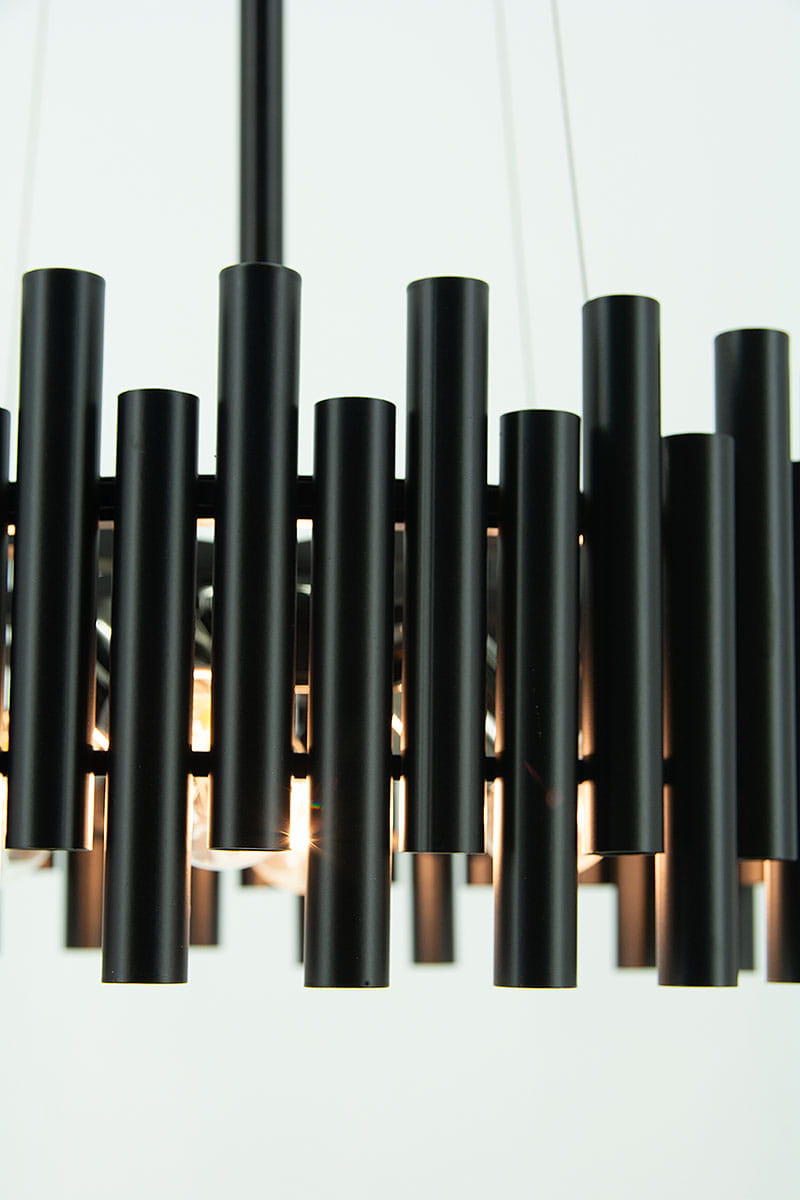 Lampa wisząca Narni w kolorze czarnym, zbudowana z cylindrycznych elementów, zawiera cztery oprawy E27. Ujęcie z bliska, pokazujące detale konstrukcji oraz źródła światła, zawieszona na cienkim przewodzie. Tło jasne, neutralne.