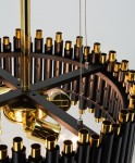 Lampa wisząca Narni 4xE27 w kolorze czarnym i złotym. Konstrukcja z metalowymi elementami, z widocznymi złotymi detalami na górze. Ujęcie zbliżeniowe z góry, ukazujące mocowanie i osłonki żarówek. Na tle jasnej powierzchni.
