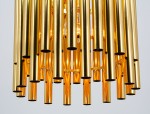 Lampa wisząca Narni 1xE27 w kolorze złotym, składająca się z metalowych rur o połyskującej powierzchni, zawieszona na równym poziomie. Widoczne wnętrze z żarówką, efektowny design w nowoczesnym stylu.