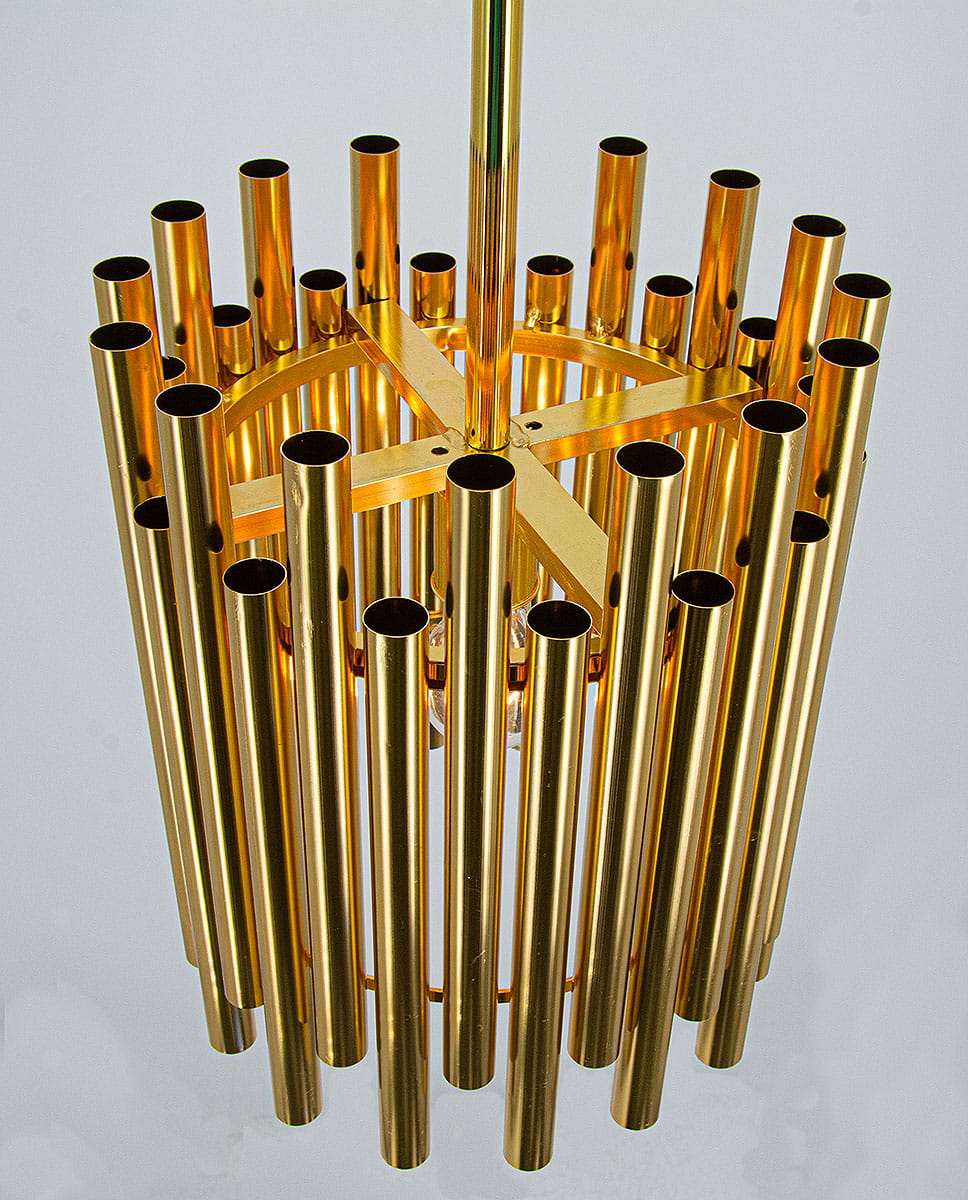Lampa wisząca Narni 1xE27 w kolorze złotym, składająca się z długich, cylindrycznych rur, ułożonych w okrąg. Produkt widoczny z góry, zawieszony na metalowym stelażu. Idealna do nowoczesnych wnętrz.