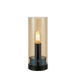 Lampa stołowa w kolorze czarnym i bursztynowym, z cylindrycznym kloszem. Zawiera źródło światła E14, umieszczone na metalowej podstawie. Widoczny przezroczysty klosz podkreśla elegancki kształt lampy. Ujęcie frontalne.