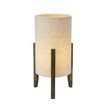 Lampa stołowa Eruca o cylindrycznym kształcie, z materiałowym kloszem w kolorze beżowym na brązowej, drewnianej podstawie. Ustawiona w pionie, emituje ciepłe światło. Idealna do wnętrz w stylu skandynawskim.