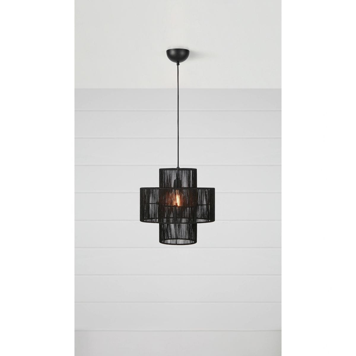 Lampa wisząca Soga 1xE27 w kolorze czarnym, o okrągłym kształcie, z transparentnym abażurem z cienkich pasków. Zawieszona na długim kablu, z widoczną żarówką wewnątrz. Tło w jasnym kolorze, minimalistyczne.