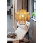 Lampa wisząca Soga z jedną oprawą E27, w naturalnym kolorze, z plecioną konstrukcją z cienkich prętów. Zawieszona nad wygodnym fotelem, emituje ciepłe światło. Widoczna w aranżacji z drewnianym stolikiem i roślinnością w tle.
