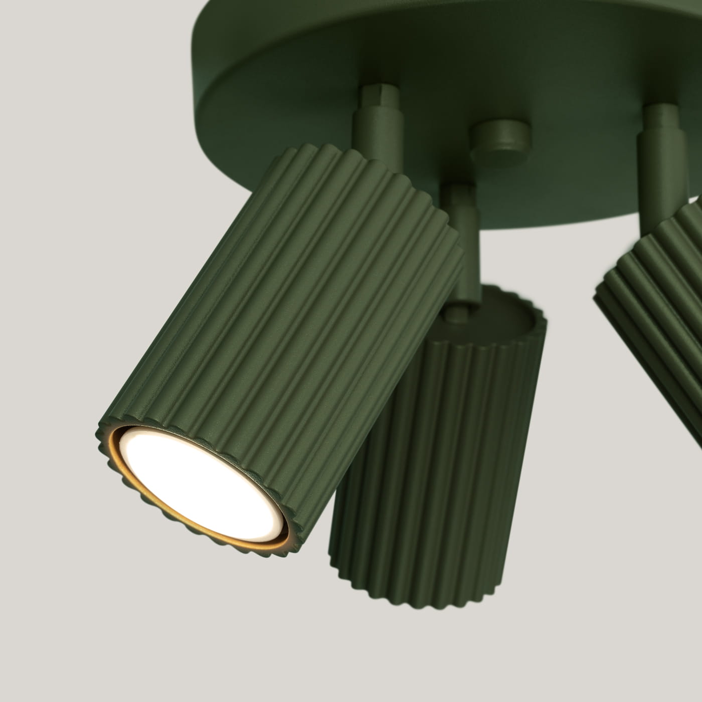 Lampa sufitowa Karbon w kolorze oliwkowym z trzema ruchomymi kloszami GU10. Klosze mają teksturowaną powierzchnię z poziomymi rowkami, umieszczone na okrągłej podstawie. Produkt widoczny z boku, uwydatniający detale konstrukcji.