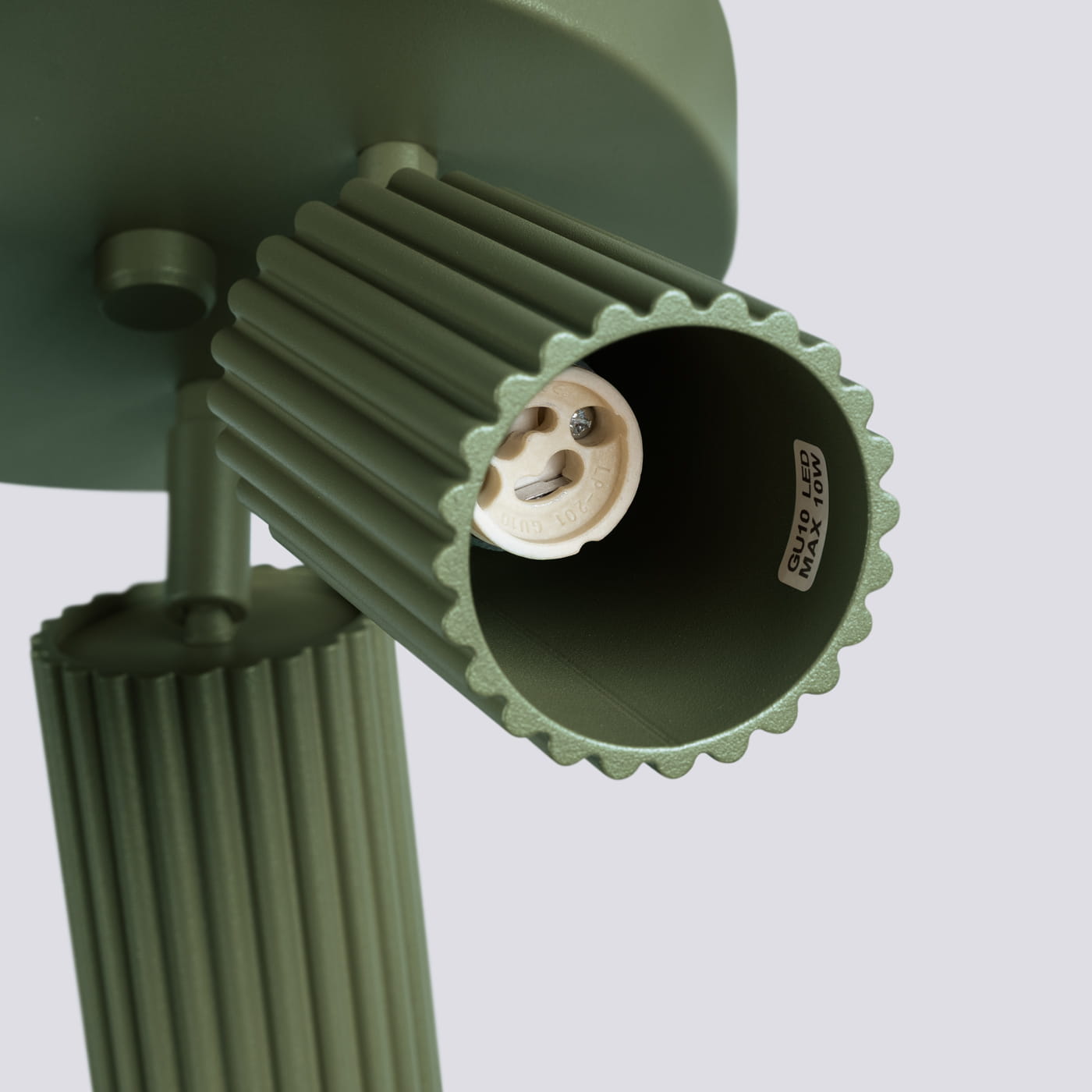 Lampa sufitowa Karbon, kolor oliwkowy, z trzema uchwytami GU10. Ujęcie z boku, ukazujące teksturowane klosze w kształcie cylindrów. Widoczny gwint do żarówek, oznaczenia maksymalnej mocy 10W. Prosta, elegancka konstrukcja.