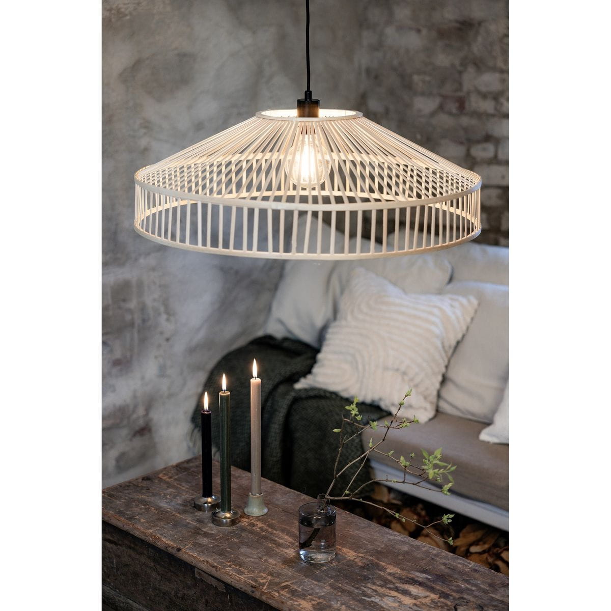 Lampa wisząca Tapa 1xE27 w naturalnym kolorze, o okrągłym, ażurowym kloszu. Zawieszona nad drewnianym stolikiem, w tle widoczna sofa z poduszkami, świeczniki z trzema świecami oraz wazon z gałązką.