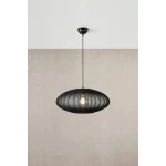 Lampa wisząca Florence D60 w kolorze czarnym, wykonana z metalowych prętów w owalnym kształcie, z widoczną żarówką E27. Zawieszona na cienkim, czarnym przewodzie, umieszczona na tle gładkiej, jasnej ściany.