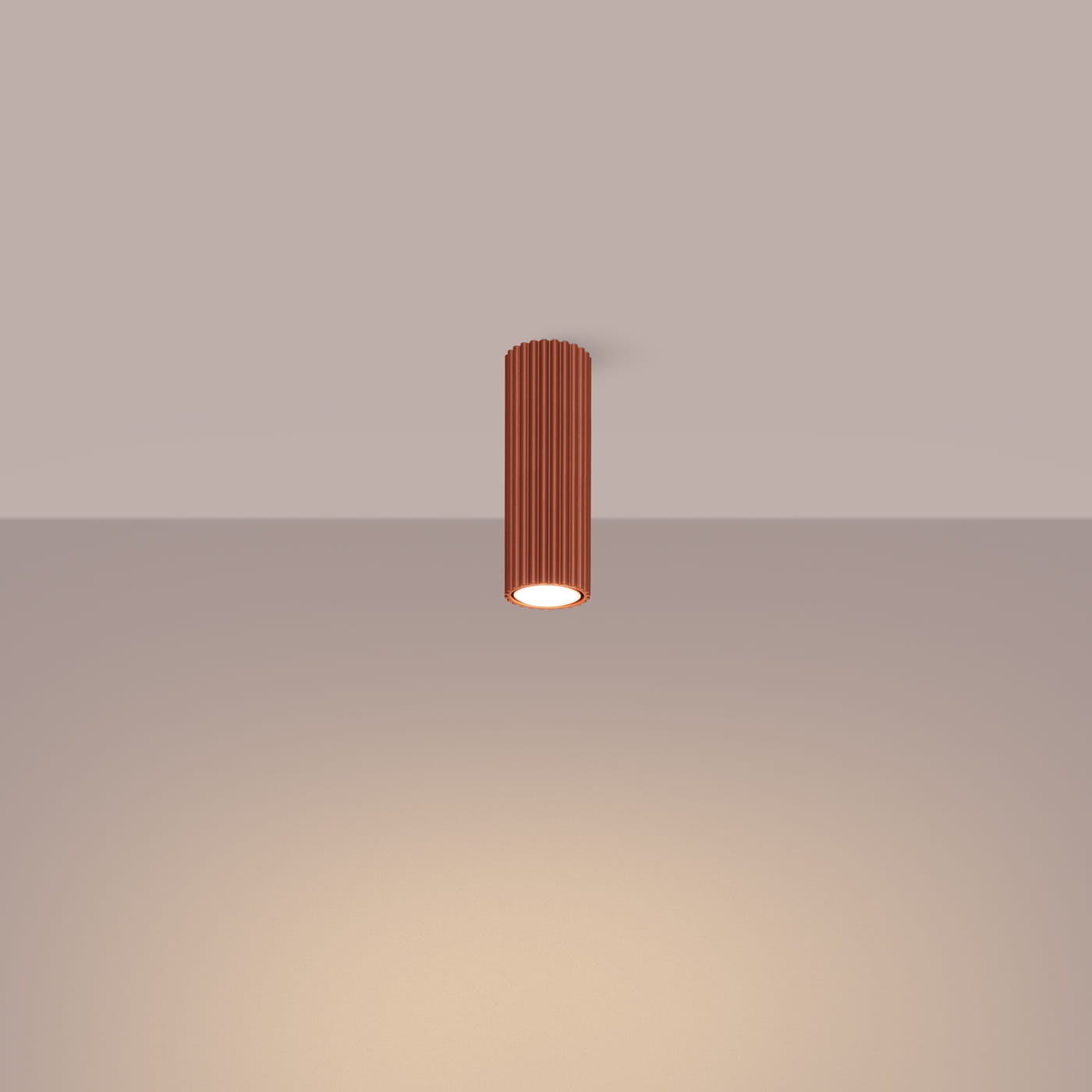 Lampa sufitowa Karbon 20 o cylindrycznym kształcie w kolorze ochry czerwonej, zawieszona pod sufitem. Posiada żarówkę GU10, z widoczną fakturą rowków na powierzchni. Światło skierowane w dół, na prostym tle.