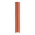 Lampa sufitowa Karbon 40 w kolorze ochra czerwona, o cylindrycznym kształcie z żebrowaną fakturą. Wysoka, z miejscem na jedną żarówkę GU10, zamontowana w pozycji wiszącej na białym tle.