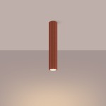 Lampa sufitowa Karbon 40 w kolorze czerwoną ochra, cylindryczna, z rowkowaną powierzchnią. Zawiera jeden gwint GU10. Umieszczona w centralnej pozycji, wisząca z sufitu, na jednolitym tle.