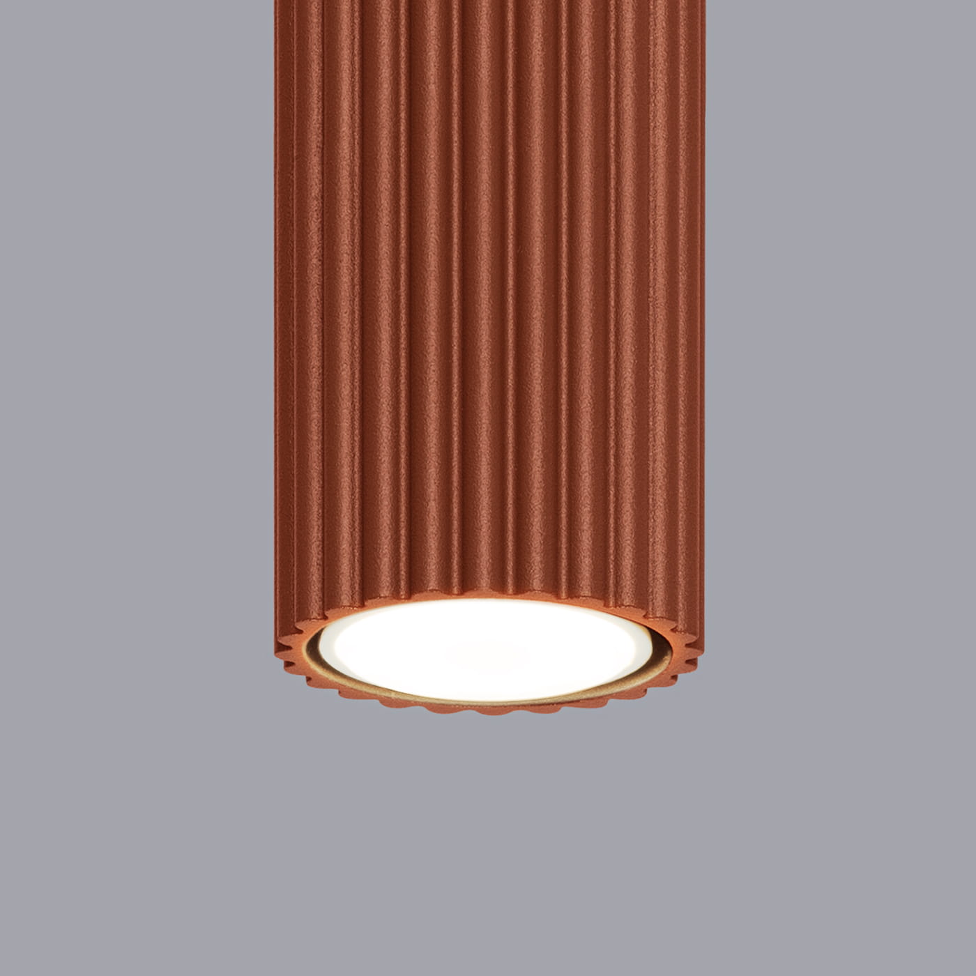 Lampa sufitowa Karbon 60 w kolorze czerwonobrązowym z teksturowaną, falistą obudową. Posiada gniazdo na żarówkę GU10, z okrągłym, białym kloszem na dole. Ujęcie z bliska, pokazujące detale i fakturę lampy na jednolitym, szarym tle.