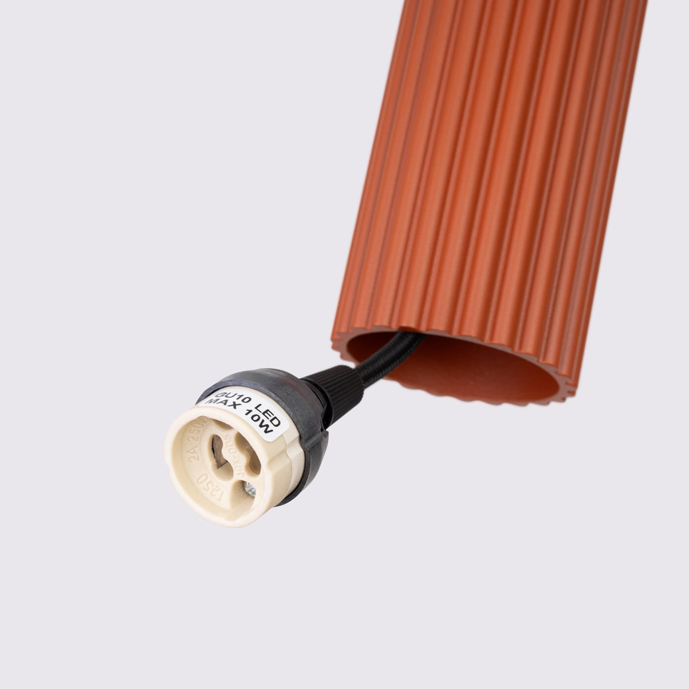 Lampa wisząca Karbon 1 w kolorze ochra czerwona, z okrągłym kloszem o żłobionej fakturze. Widoczny gwint GU10 do żarówki LED, z oznaczeniem maksymalnej mocy 10W. Kąt widzenia z boku, na jednolitym tle.