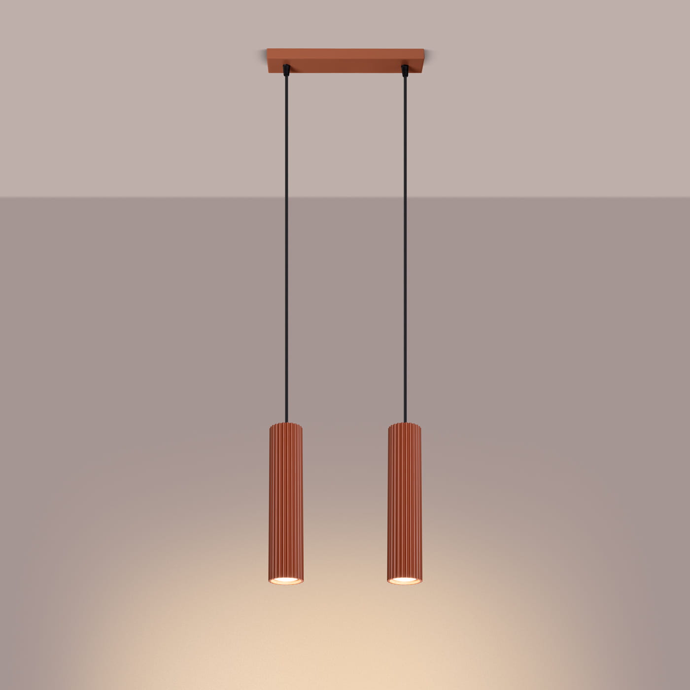Lampa wisząca Karbon 2 w kolorze ochra czerwona, z dwoma cylindrycznymi kloszami z pionowymi żłobieniami, zawieszona na czarnych linkach. Klosze mają oprawy na żarówki GU10. Ujęcie frontalne, na prostym tle.