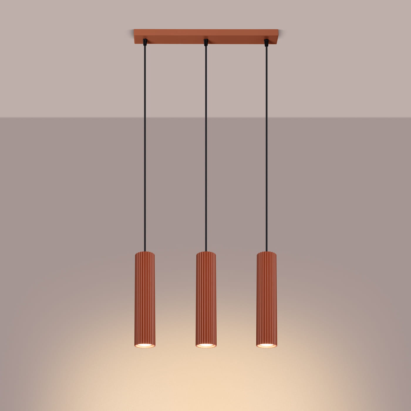Lampa wisząca Karbon 3, ochra czerwona, z trzema cylindrycznymi kloszami z rowkami, zawieszona na czarnych linkach. Montaż sufitowy, subtelne oświetlenie w tle. Idealna do nowoczesnych wnętrz.