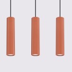 Lampa wisząca Karbon 3, w kolorze ochra czerwona, składająca się z trzech cylindrycznych kloszy z pionowymi żłobieniami. Klosze zawieszone na czarnych przewodach, w frontalnym ujęciu na jasnym tle. Idealna do nowoczesnych wnętrz.
