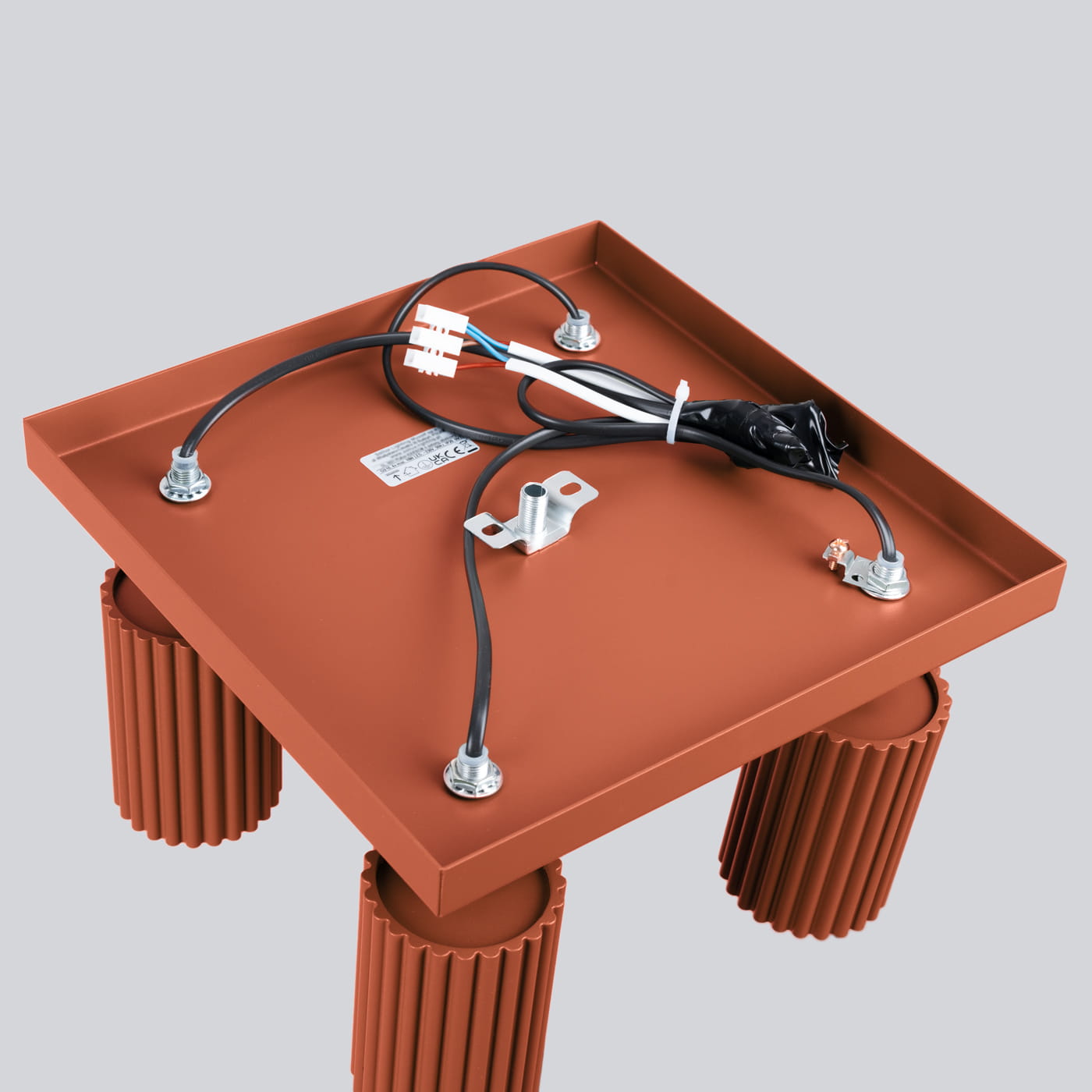 Czerwona lampa sufitowa Karbon L z czterema miejscami na żarówki GU10. Widok od spodu, z widocznymi kablami, metalowymi mocowaniami i teksturą podstawy w formie żeber. Prosta konstrukcja, montażowy element centralny.