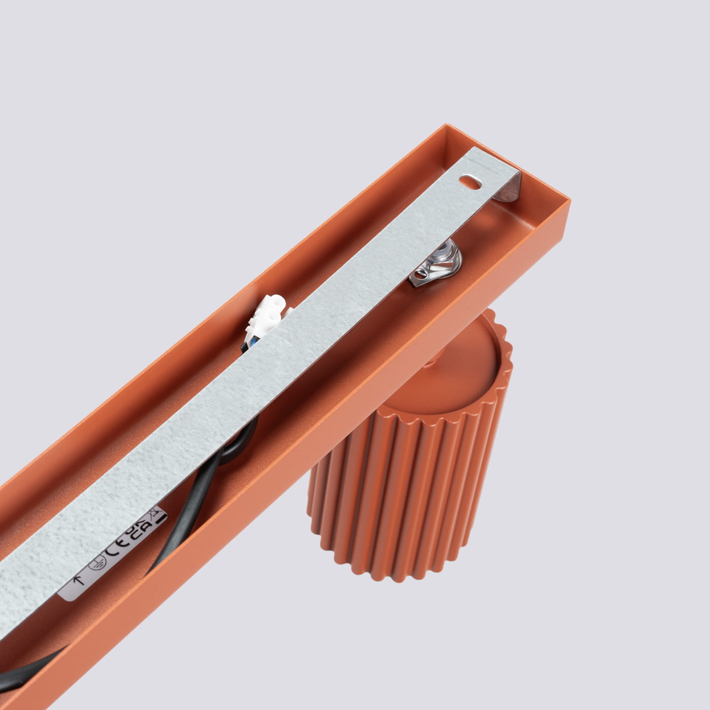 Lampa sufitowa Karbon L w kolorze ochra czerwona, z miejscem na cztery żarówki GU10. Ujęcie z góry, z widoczną metalową listwą montażową oraz dekoracyjnym, żebrowanym elementem. Prosta konstrukcja, idealna do nowoczesnych wnętrz.