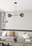 Lampa wisząca Xotic 2xE27 w kolorze czarnym, z podwójnymi okrągłymi kloszami z wzorem. Zawieszona na dwóch cienkich linkach, umieszczona nad stolikiem w nowoczesnym wnętrzu z jasną sofą i regałem w tle.