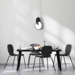 Czarna lampa wisząca Circlo z jedną żarówką LED 8W, umieszczona nad stołem w minimalistycznej jadalni. Lampa ma okrągły kształt z półprzezroczystym elementem, wisząca na cienkim kablu, w otoczeniu czarnych krzeseł i stołu.