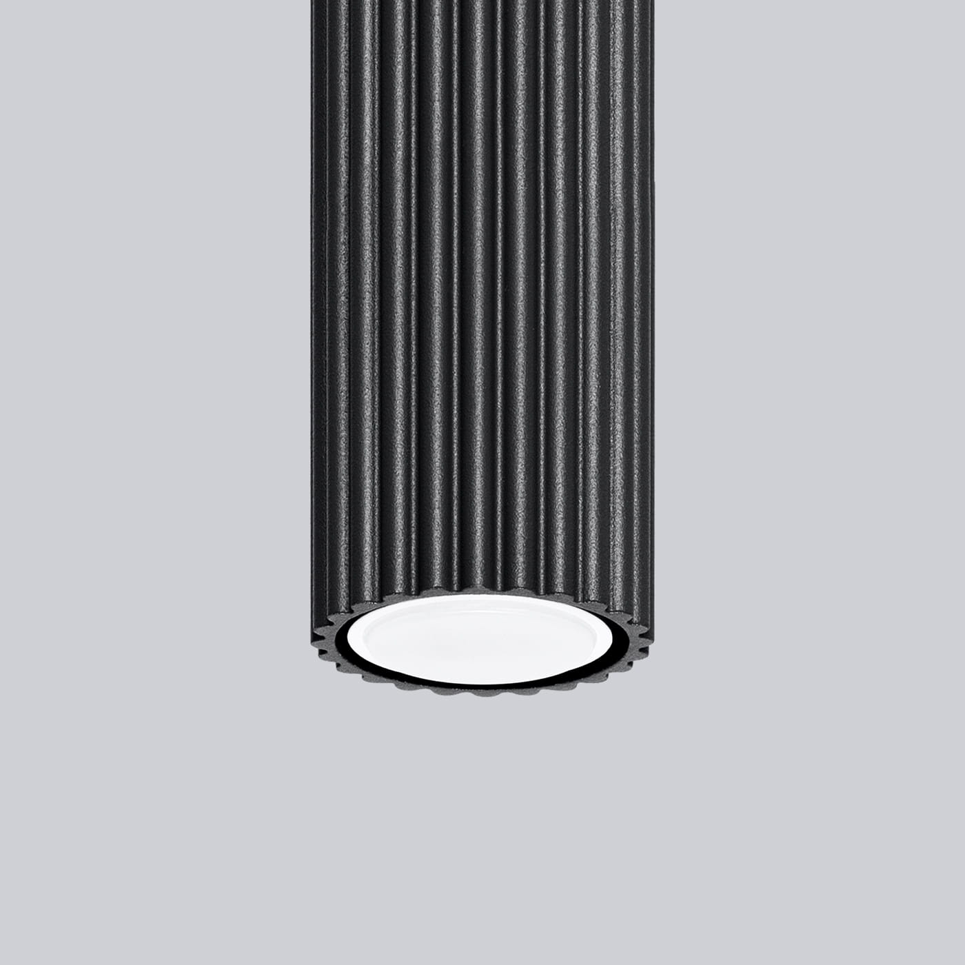 Lampa sufitowa Karbon 10 o cylindrycznym kształcie, wykonana z czarnego materiału z teksturą rowkowaną. Posiada miejsce na jedną żarówkę GU10, widoczne białe wnętrze oprawy. Wisi w pozycji pionowej na jednolitym tle.