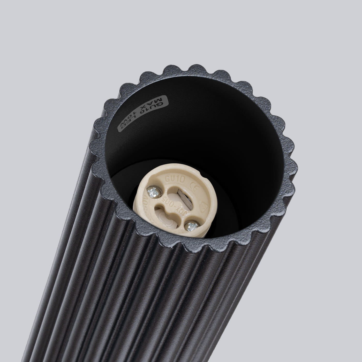 Czarna lampa sufitowa Karbon 10 l z oprawą na żarówkę GU10. Widoczna faktura w formie żłobień na cylindrycznej obudowie oraz ceramiczny gwint w jasnym kolorze. Zdjęcie zbliżeniowe na górną część lampy.