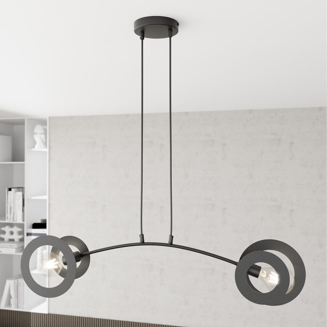 Lampa wisząca Euforia w kolorze czarnym z dwoma oprawami na żarówki E27. Charakteryzuje się nowoczesnym designem z okrągłymi elementami. Produkt zawieszony na dwóch przewodach, z okrągłą podsufitką, na jasnym tle.