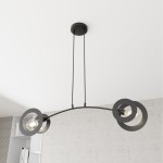 Lampa wisząca Euforia w kolorze czarnym, z dwoma oprawami E27. Posiada zaokrągloną metalową konstrukcję z trzema okrągłymi elementami, zawieszona na dwóch linkach. Ujęcie z dołu, na jasnym tle.