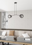 Lampa wisząca Euforia w kolorze czarnym, z dwoma oprawami E27. Ma nowoczesny, łukowaty kształt z okrągłymi elementami. Zawieszona na długich linkach, idealna do wnętrz. Tło jasne, minimalistyczne, z sofą i stolikiem.