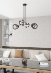 Lampa wisząca Euforia w kolorze czarnym, z czterema oprawami na żarówki E27, zawieszona na długich linkach. Okrągłe klosze w różnych rozmiarach tworzą nowoczesny wzór. Produkt umieszczony w aranżacji salonu z jasną sofą i szklanym stolikiem.