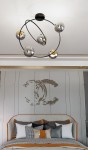 Lampa sufitowa Stardom z pięcioma kloszami E14 w kolorze czarnym i grafitowym, z metalową konstrukcją w kształcie okręgu. Widok z góry, montowana na suficie, w eleganckim wnętrzu z dekoracyjną ścianą w tle.