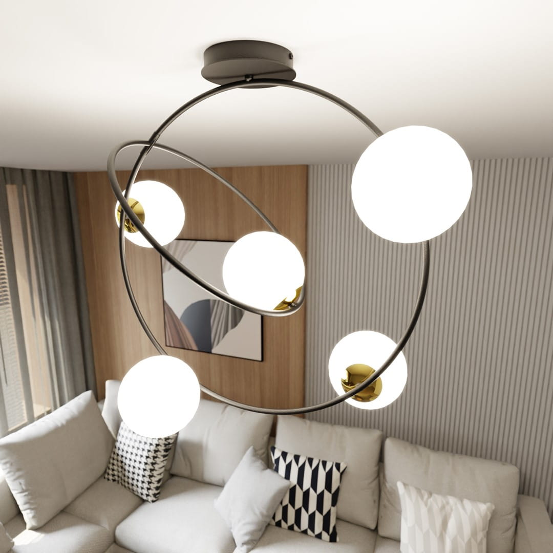 Lampa sufitowa Stardom w kolorze czarnym i białym, z pięcioma okrągłymi kloszami, zawieszona na okrągłej podstawie. Klosze białe, metalowe mocowania w kolorze złotym. Ujęcie z góry, w tle widoczny jasny salon z sofą i dekoracyjnymi poduszkami.