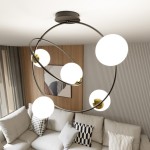 Lampa sufitowa Stardom w kolorze czarnym i białym, z pięcioma okrągłymi kloszami, zawieszona na okrągłej podstawie. Klosze białe, metalowe mocowania w kolorze złotym. Ujęcie z góry, w tle widoczny jasny salon z sofą i dekoracyjnymi poduszkami.