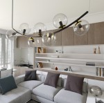Lampa wisząca Ritz z siedmioma źródłami światła E14, w kolorze czarnym i transparentnym. Posiada okrągłe, szklane klosze i eleganckie mocowania na czarnej podstawie. Zawieszona w nowoczesnym wnętrzu, nad narożną sofą z poduszkami.