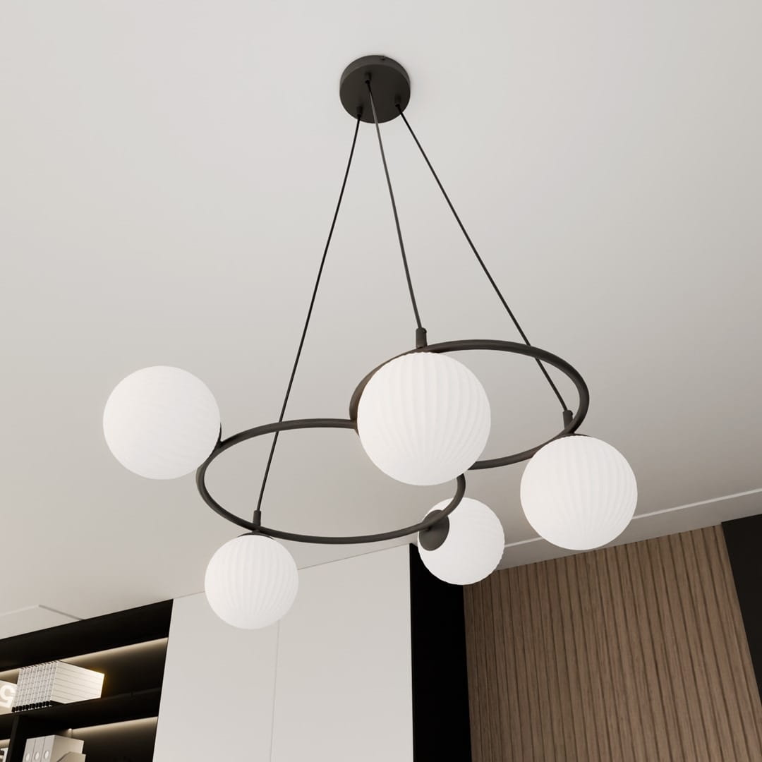 Lampa wisząca Libra z pięcioma opalowymi kloszami w kształcie kul, zawieszona na czarnych metalowych obręczach. Ujęcie z dołu, ukazujące nowoczesny design i elegancką formę. Tło jasne, z elementami wnętrza w stonowanych kolorach.
