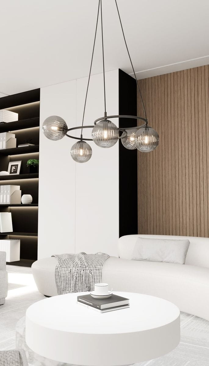 Lampa wisząca Libra 5xE14 w kolorze czarnym i grafitowym, z pięcioma okrągłymi kloszami w przezroczystym, teksturowanym szkle. Wisi na cienkich linkach w nowoczesnym wnętrzu, z białymi meblami i drewnianą ścianą w tle.