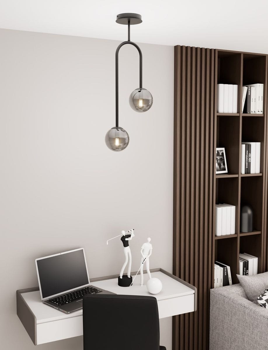 Lampa sufitowa Atria 2xE14 w kolorze czarnym i grafitowym, zawieszona na podwójnym łuku. Wyposażona w dwa szklane klosze w odcieniu szarym, umieszczona w nowoczesnym wnętrzu z biurkiem i półkami.
