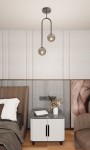 Lampa sufitowa Atria 2xE14 w kolorze czarnym i grafitowym, z dwiema szklanymi kulami na długich uchwytach. Zawieszona w nowoczesnym wnętrzu nad nocnym stolikiem, z neutralnym tłem i drewnianą podłogą.