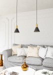 Lampa wisząca Rosa z jednym gniazdem E27, w kolorze czarnym z złotym elementem u góry. Zawieszona na cienkim przewodzie, w pozycji pionowej. Tło w jasnym wnętrzu z szarym sofą i dekoracjami na stole.