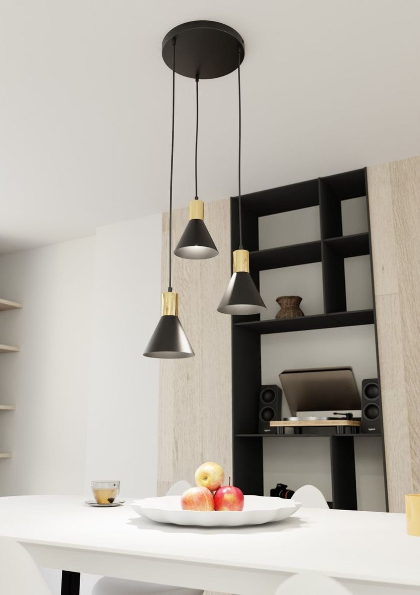 Lampa wisząca Rosa 3xE27 w kolorze czarnym i złotym. Posiada trzy stożkowate klosze zawieszone na długich kablach, montowana na okrągłej podsufitce. Umieszczona nad białym stołem, w tle widoczna półka i sprzęt audio.