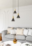 Lampa wisząca Rosa z trzema kloszami w kolorze czarnym z metalowymi złotymi elementami. Zawieszona na czarnych przewodach, umieszczona nad szarym sofą z poduszkami w neutralnych odcieniach, w jasnym wnętrzu.