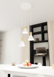 Lampa wisząca Rosa z trzema kloszami w kolorze białym i złotym, zawieszona na białych przewodach. Klosze mają stożkowaty kształt. Produkt umieszczony jest nad stołem z owocami. Tło jasne, z elementami drewnianymi i czarnymi półkami.